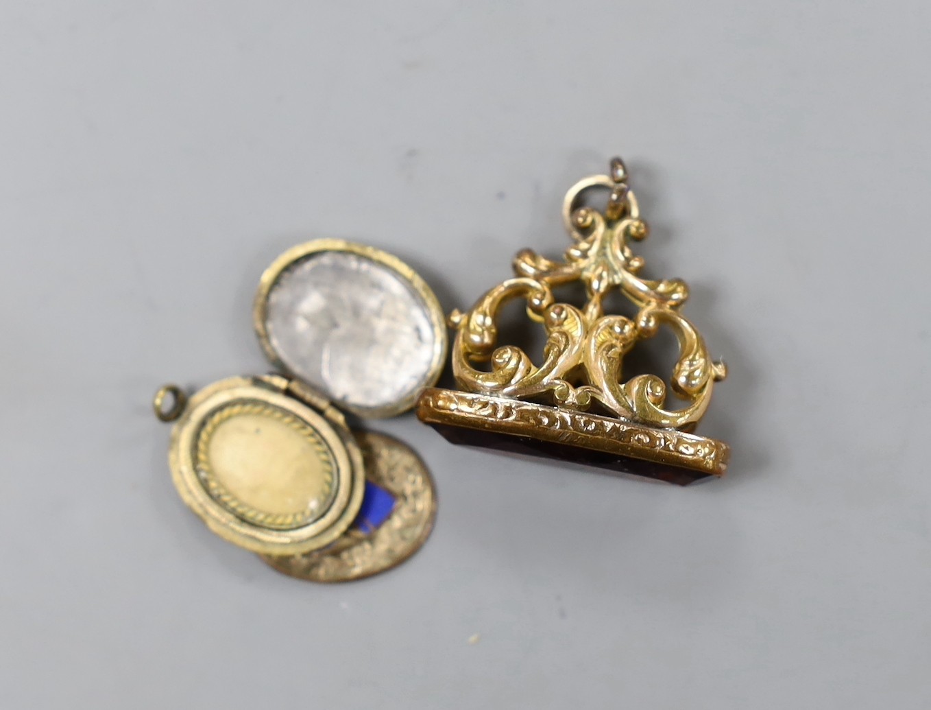 An Edwardian yellow metal and seed pearl cluster set pendant brooch, 27mm, a George V 9ct gold mounted citrine spinning fob, one other gilt metal fob and a damaged locket.